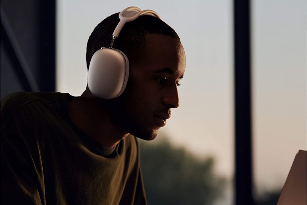 A man wearing Apple AirPods Max headphones working at a laptop