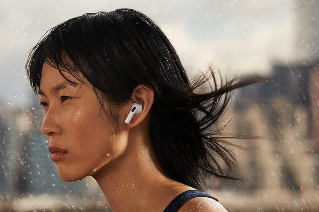 A woman runs in the rain with Apple AirPods wireless headphones