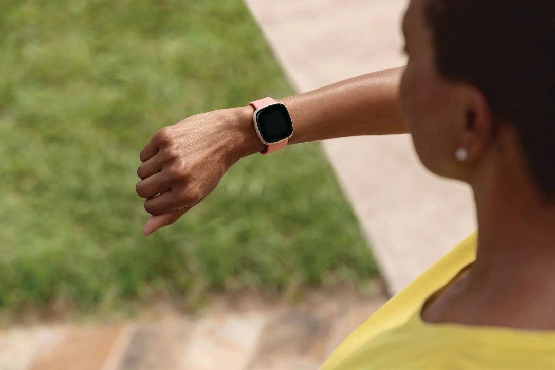 A woman looks at the screen of her Fitbit Versa 3 smartwatch